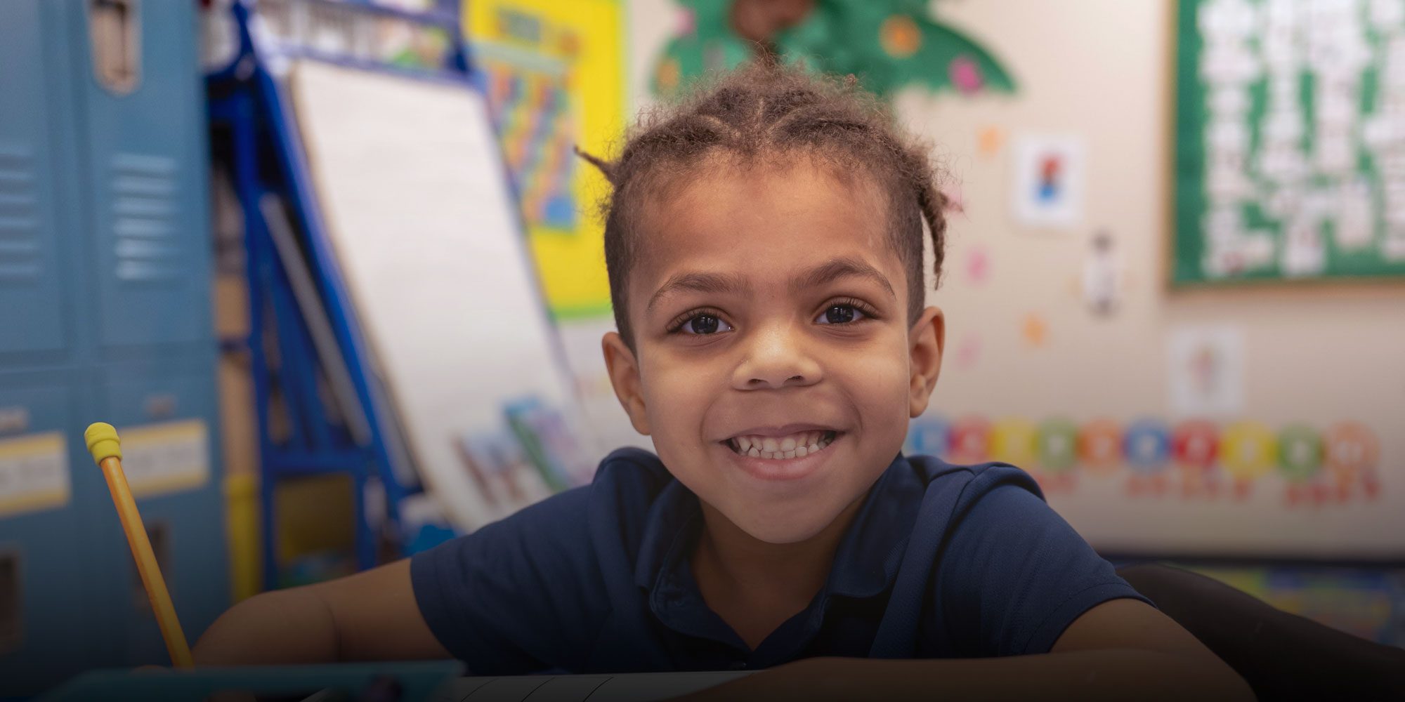 Smiling elementary student writing at desk